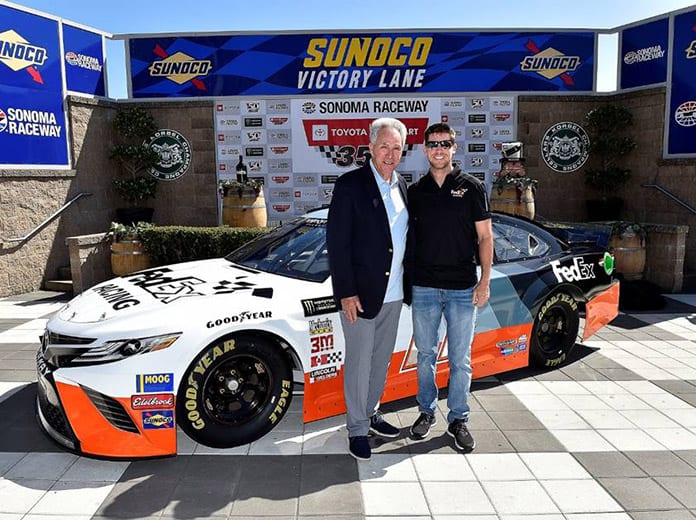 Denny Hamlin (right) and Darrell Waltrip pose in front of the car Hamlin will drive during the Bojangles Southern 500 later this year.