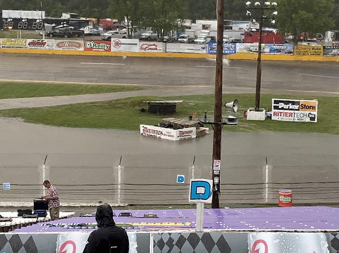 A fan picks up his chair after heavy rain and gusting winds went through the area Tuesday evening ahead of the 41st SUPERSEAL Slinger Nationals presented by Miller Lite at Slinger Super Speedway in Slinger, Wis. The race was postponed to Wednesday. (Nicholas Dettmann Photo)