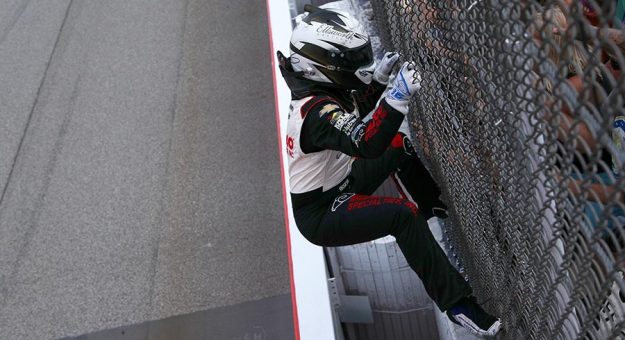 A.J. Allmendinger climbs the fence in celebration after winning Saturday's NASCAR Xfinity Series race at Michigan Int'l Speedway. (Sean Gardner/Getty Images Photo)