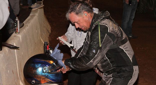 Lance Dewease attempts to clean oil off his helmet after an oil leak soaked him in oil during the Tuscarora 50. (Dan Demarco Photo)