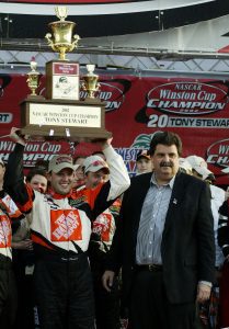 HOMESTEAD, FL - NOVEMBER 17:  Tony Stewart, driver of the #20 Home Depot Pontiac Grand Prix lifts the NASCAR Winston Cup Championship Trophy as NASCAR President Mike Helton looks on after Stewart won the NASCAR Winston Cup Championship at the NASCAR Winston Cup Series Ford 400 at the Homestead-Miami Speedway on November 17, 2002 in Homestead, Florida.(Photo by Robert Laberge/Getty Images). | Getty Images